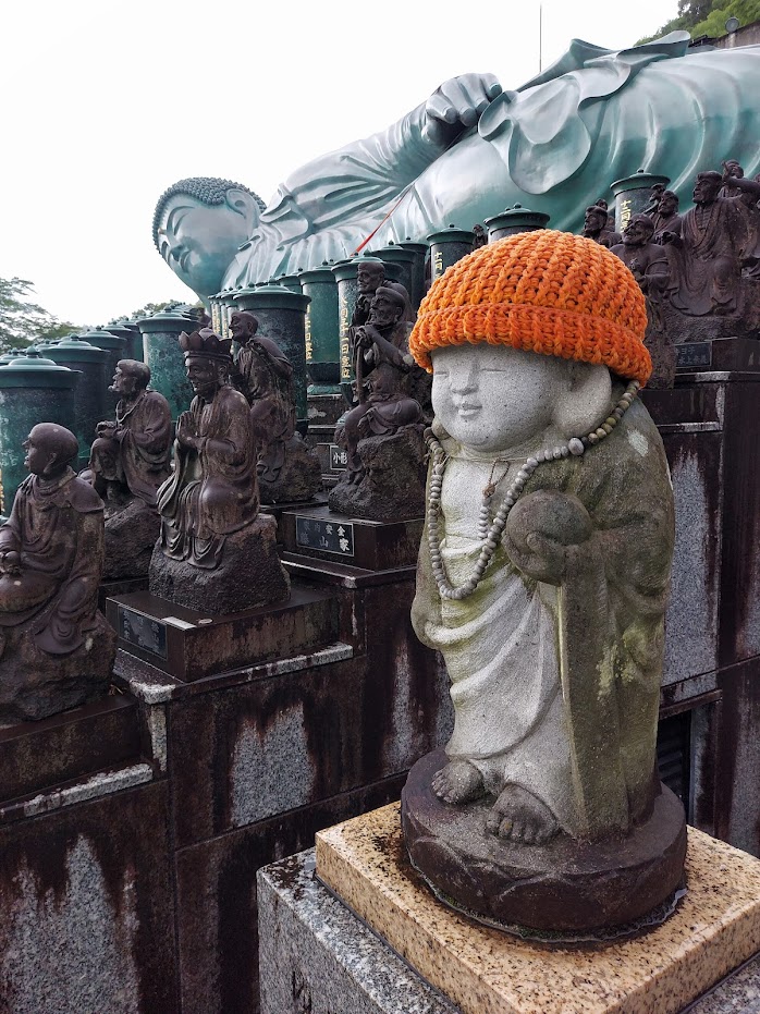 Billede af buddha statuer i forskellige størrelser ved Nanzoin templet udenfor Fukuoka, Japan. Den lille status har en orange hue på.