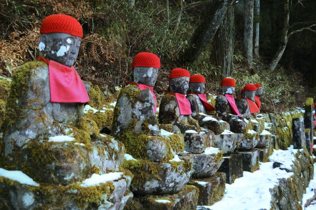 gamle jizo statuer beklædt med strik hue og hagesmæk