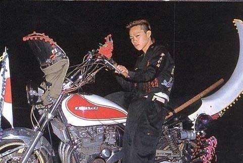 Japansk Bōsōzoku biker medlem med stort hår, og klassisk udsmykket motorcykel og tøj
